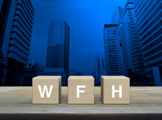 WFH acronym on wood block cubes on wooden table over modern office city tower and skyscraper, Business work from home concept