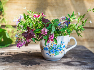 Summer small bouquet of wild flowers in a mug with floral decor
