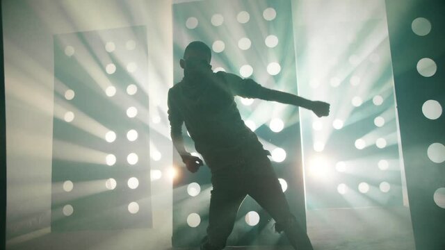 Professional Hip Hop , freestyle or swag dancer . Stylish young man dancing near decorative walls with many circle holes and spotlight . Real decoration . Shot on RED HELIUM Camera in Slow Motion .