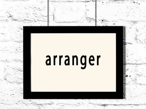 Black frame hanging on white brick wall with inscription arranger