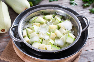 Boiled vegetables, zucchini in a colander in ice water after blanching. Frozen Food