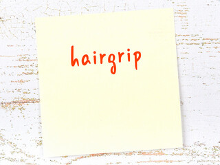 Yellow sticky note on wooden wall with handwritten word hairgrip - obrazy, fototapety, plakaty