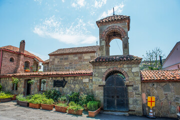 An old stone bell tower. Clay tile. Wooden gate with wrought iron elements. Plant pots.