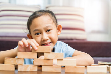 Happy Asian girl play wooden blocks at home