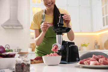 Young woman using modern meat grinder in kitchen, closeup