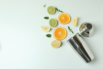 Shaker with citrus cocktail ingredients on white background