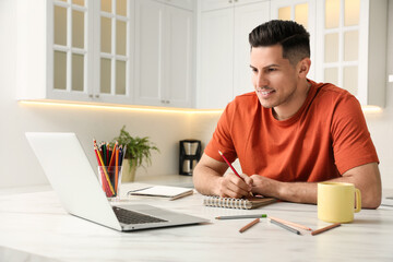 Man drawing in notebook at online lesson indoors. Distance learning