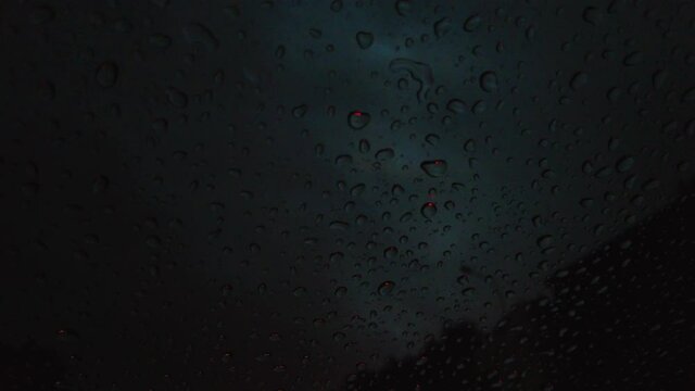 drops on a window glass during a rain thunderstorm in the evening against a background of thunderclouds in the sky