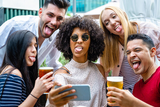 crazy selfie time of a millennials group of friends, people drinking beers and having fun using smartphone for making memories