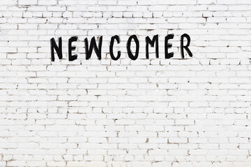 Inscription newcomer painted on white brick wall