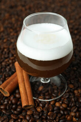 Glass of Irish coffee and cinnamon on coffee seeds background