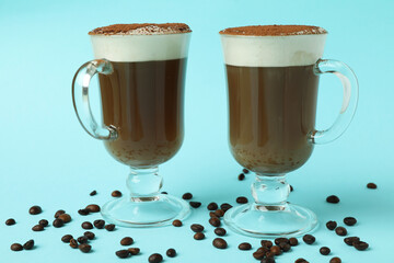 Glasses of irish coffee and coffee seeds on blue background
