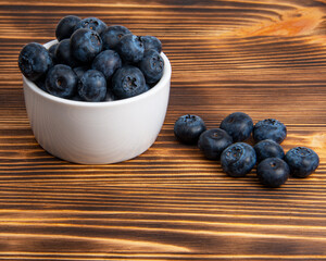 Fresh blueberry in white dish on wooden background