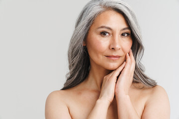 Mature shirtless woman with grey hair posing and looking at camera