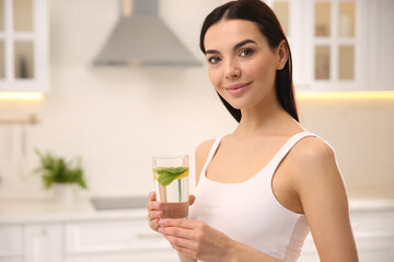 Young woman with glass of fresh lemonade at home