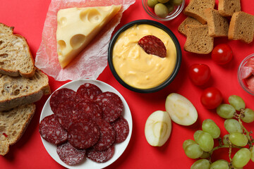 Concept of delicious food with fondue on red background