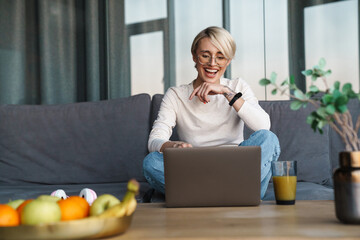 Smiling mod aged blonde woman studying online