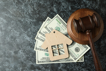 Judge gavel, dollars and wooden house on black smokey table