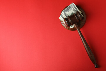 Judge gavel with dollars on red background