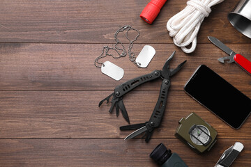 Flat lay composition with compact portable multitool and accessories on wooden background. Space for text