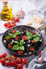 Black spaghetti pasta with tomatoes, cheese and basil