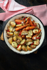 Oven baked potatoes, carrots, garlic, onions with chili, thyme and rosemary