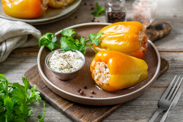 Sweet pepper stuffed with rice and ground beef, in a ceramic plate on a light gray wooden table