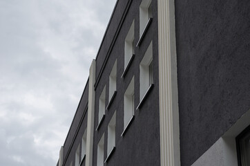 Dark-gray building with white windows against an overcast sky. R