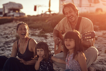 Family on a vacation, singing, playing music on a guitar and enjoying summertime vibes.