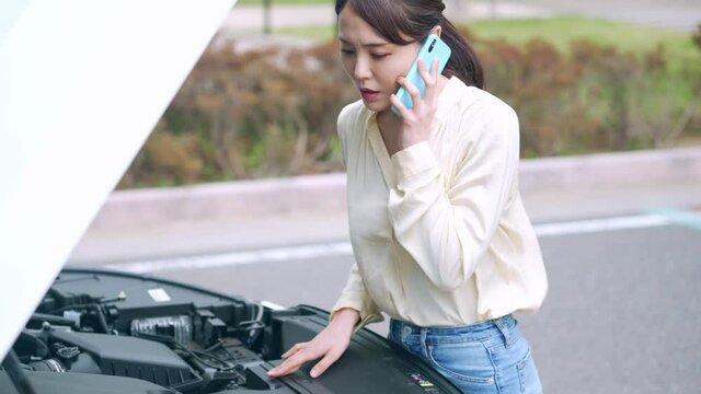 自動車のボンネットを開ける女性　故障　ロードサービス