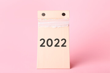 Tear-off calendar at the end of the year with 2022 on color background. Concept of new years goals