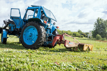 Old tractor with mover cutting grass in agriculture field.