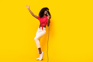 Fototapeta na wymiar Full body photo of afro american young woman wear sunglass hold mic sing isolated on yellow color background