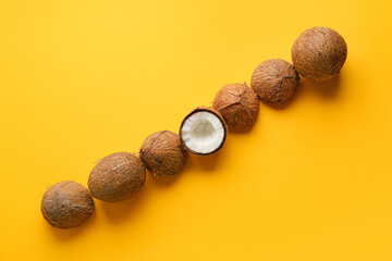 Broken coconut among whole ones on color background. Concept of uniqueness