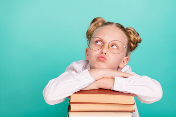 Photo of sad small girl with books look empty space wear white shirt spectacles isolated on teal background