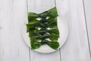 Green kelp knot for Asian marine cuisine - obrazy, fototapety, plakaty