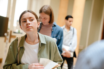 Young european students standing in line at library