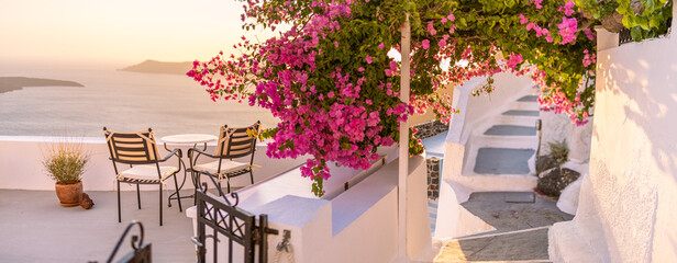 Beautiful landscape panorama Caldera romantic scenery sunset Aegean sea, Santorini. Couple travel vacation, honeymoon destination. Romance with flowers, two chairs table and sea view. Luxury holiday
