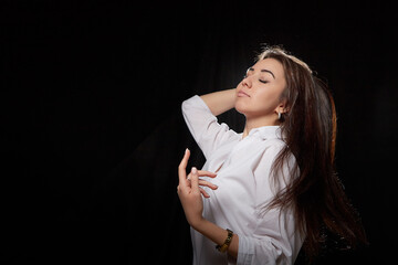 Beautiful girl with long hair posing in studio on a black background