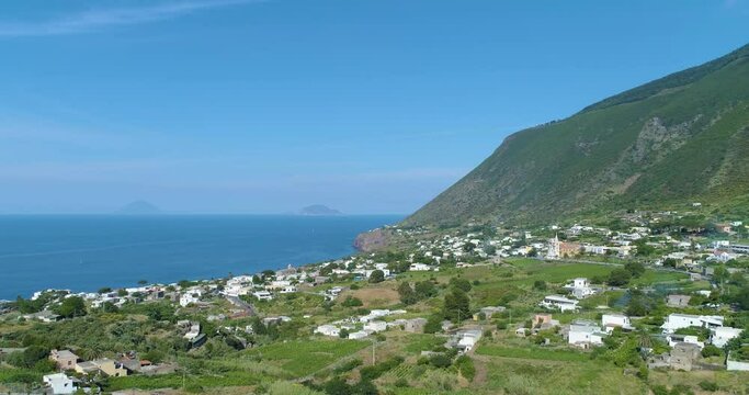 Panoramic aerial view of Salina coastline, summer and sunny day. Tipical white houses i hinterland, blue sea on the side and green mountain in background