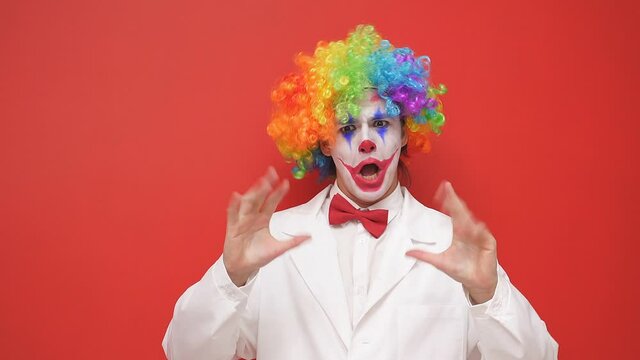Playful clown makes grimaces on an isolated background