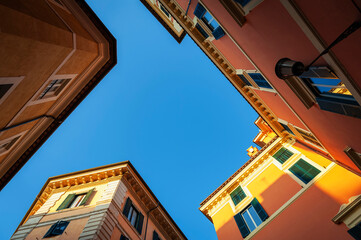 Low angle shot of old buildings in pastel colours and blue sky on Pastini street (Via dei Pastini) in historic centre of Rome, Italy