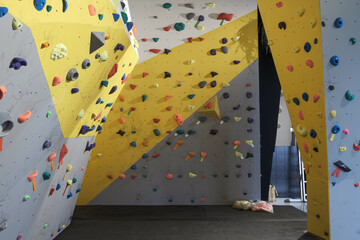 Empty gray and yellow bouldering walls with colorful handles © Tossal Studio/Wirestock