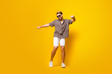 Fototapeta na wymiar Full length photo of funny sweet young guy wear leopard outfit dark eyewear smiling dancing isolated yellow color background