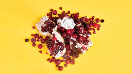 A mix of pomegranate seeds and frozen cranberries on a yellow background. Suitable for advertising juice, smoothie recipes. The concept of healthy eating.