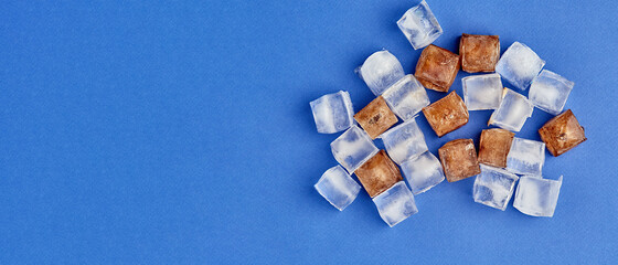Frozen cola in cubes. Ice lies on a colored background with a place to copy, panoramic view,...