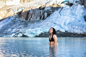 Adventurous White Caucasian Adult Woman Swimming in Ice Cold Glacier Lake on top of a Mountain. Wedgemount, Whistler, British Columbia, Canada.