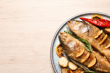 Tasty homemade roasted perches with garnish on wooden table, top view and space for text. River fish