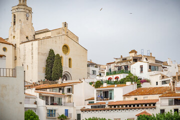 Fototapeta premium Casas blancas y mar azul en el puerto de Cadaqués con la iglesia y la playa, Costa Brava, España