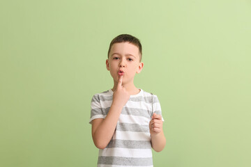Little boy with logopedic tool for speech correction on color background
